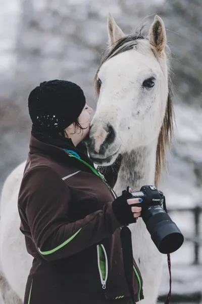 Fotografin Tierfotografin Jennifer Raßmann-Wagner beim Pferdefotoshooting im Schnee mit Kamera und Araber